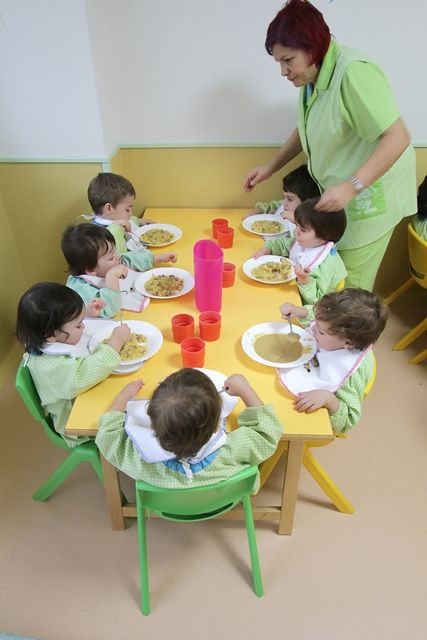 Escuela Infantil Los Robles mujer dando de comer a niños